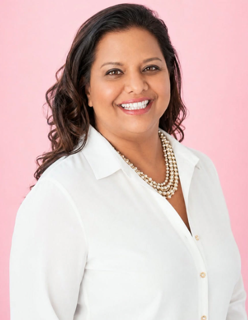Karen Baring smiling in a white blouse and pearl necklace
